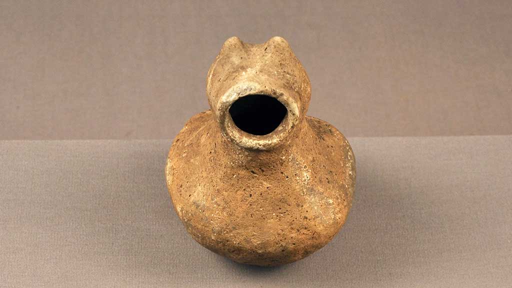 unadorned stone figure with pointy ears and a large open round mouth