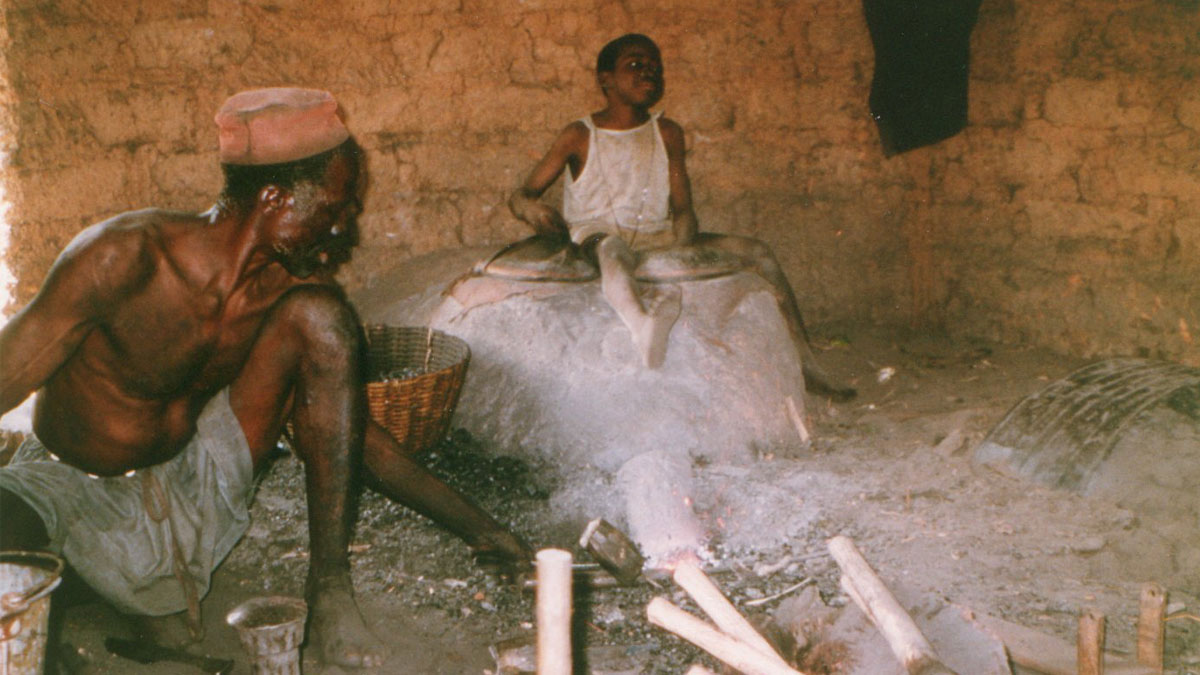 a boy observing a blacksmith at work